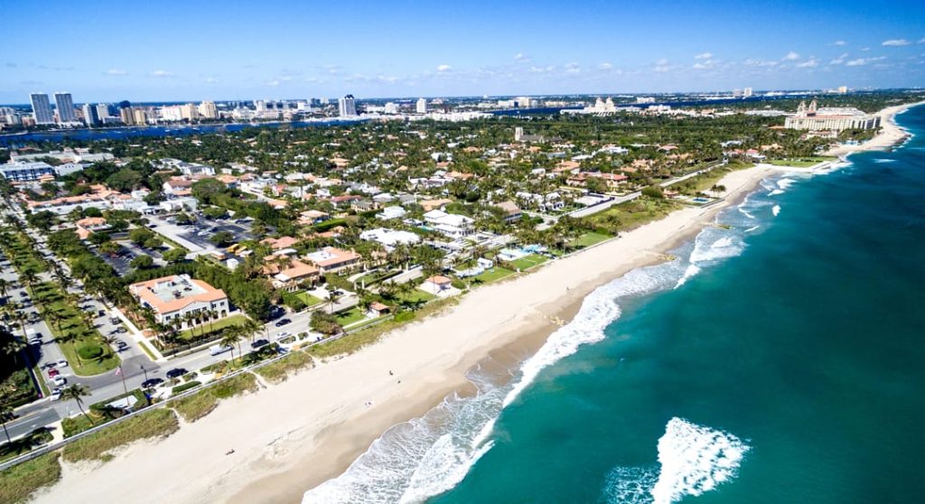 Luchtfoto van luxe villa's en een breed zandstrand langs de turquoise kustlijn van Palm Beach
