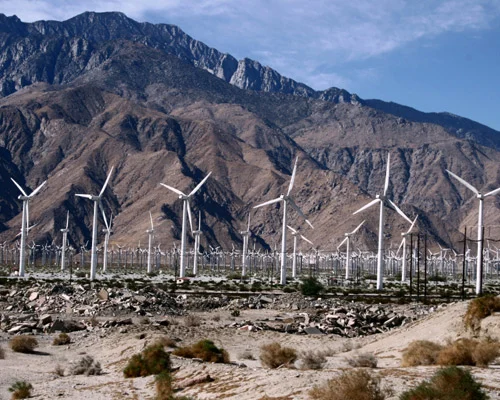 Rijen witte windturbines in de woestijn met kale bergen op de achtergrond bij de San Gorgonio Pass nabij Palm Springs