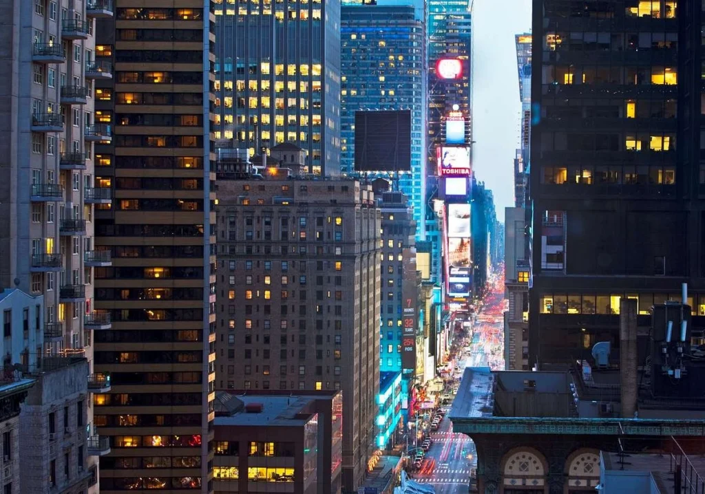 Nachtelijk uitzicht op de verlichte wolkenkrabbers en neonreclames van Times Square, gezien vanuit een hotelraam in Midtown Manhattan