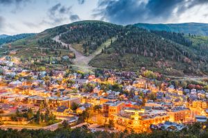 Luchtfoto van het verlichte centrum van Park City tegen een beboste berghelling bij schemering