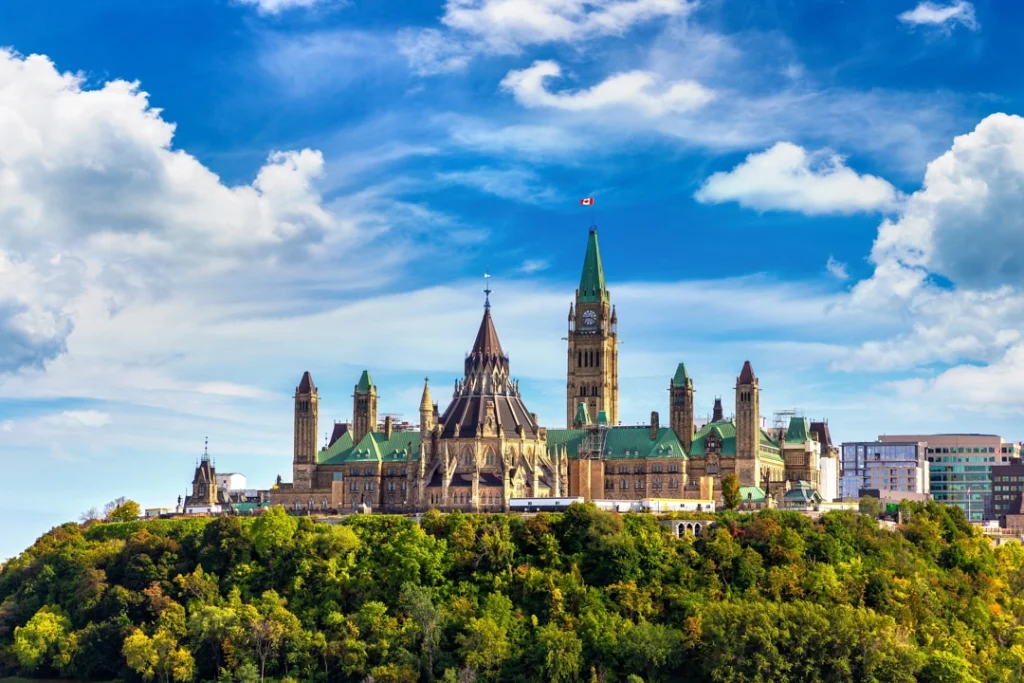 Het Canadese parlementsgebouw op Parliament Hill in Ottawa, gezien vanaf de rivier tussen bomen