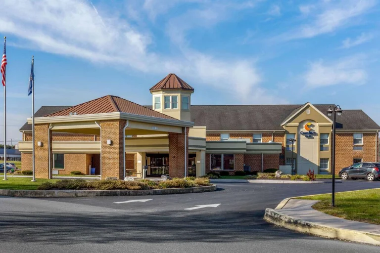 Bakstenen Comfort Inn hotel met een torentje, een Amerikaanse vlag en een lege parkeerplaats onder een blauwe lucht in Pennsylvania
