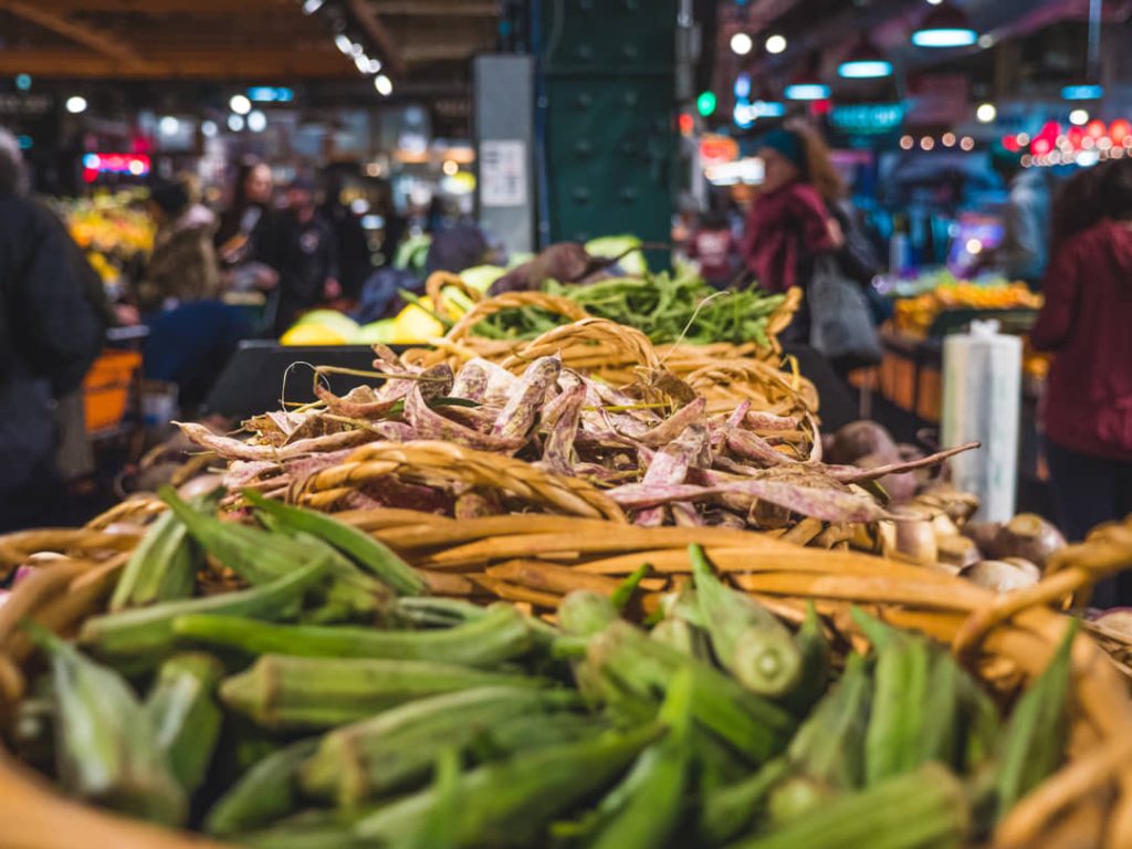 Rieten manden vol okra en boontjes op een marktkraam met bezoekers op de achtergrond in Reading Terminal Market