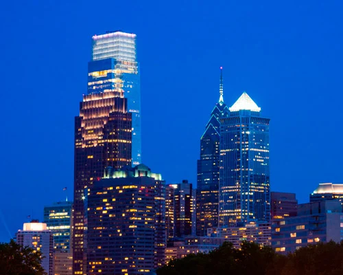 Verlichte hoge wolkenkrabbers van het centrum van Philadelphia tegen een donkerblauwe avondlucht