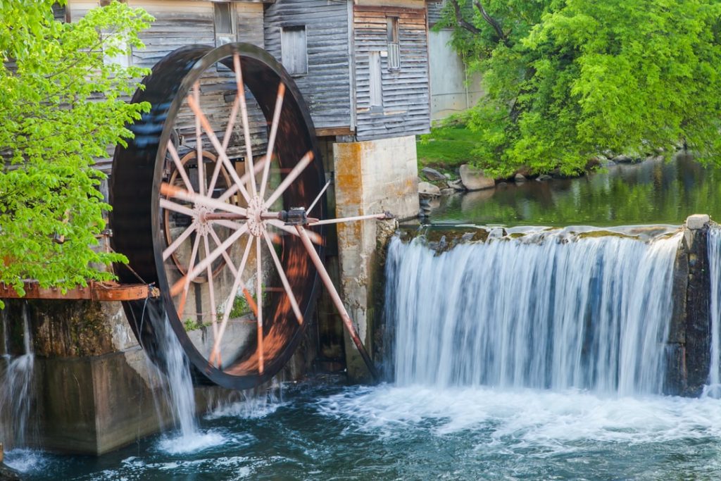 Groot houten waterrad van de historische Old Mill in Pigeon Forge met stromend water dat over een waterval valt tussen groen gebladerte