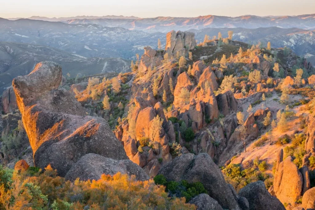 Grillige rotspieken en rotsblokken kleuren goudbruin in het licht van de ondergaande zon in Pinnacles National Park
