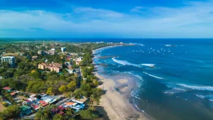 Luchtfoto van een kustdorp met gebouwen tussen het groen langs een baai vol zeilbootjes bij Playa Flamingo in Guanacaste