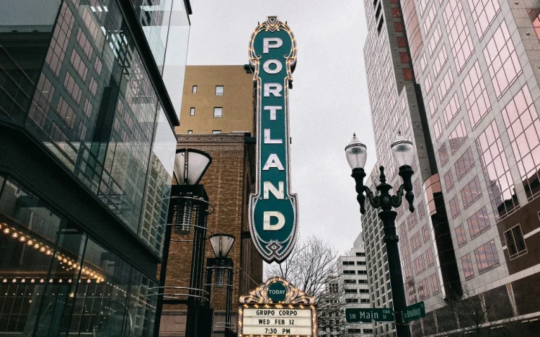 Groot verticaal neonbord met de tekst Portland tussen gebouwen en straatlantaarns in de binnenstad van Portland in Oregon