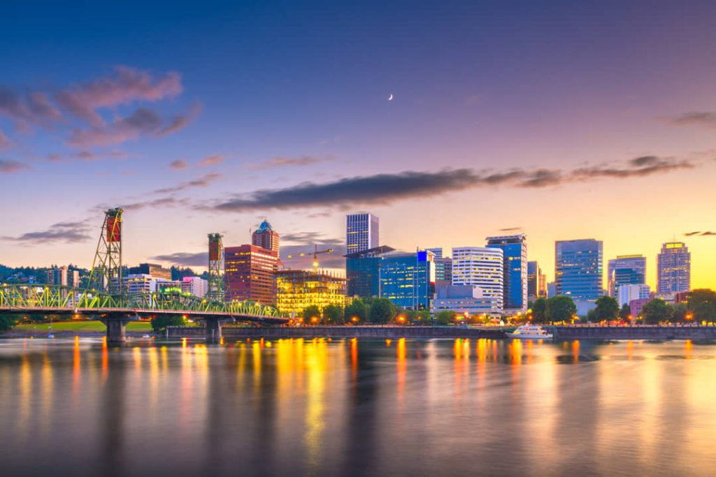 Skyline van Portland weerspiegeld in de rivier bij zonsondergang, met de groene Hawthorne Bridge op de voorgrond