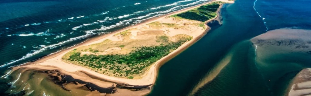 Luchtfoto van een smalle groene zandbank omringd door golvend blauw water bij Prince Edward Island