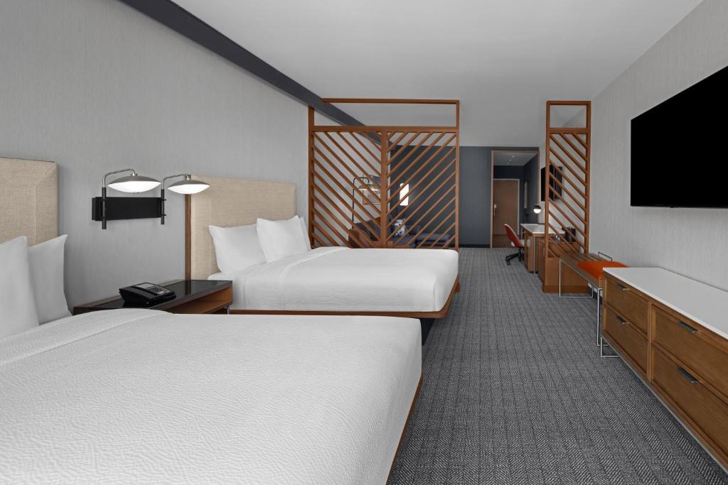 Hotelkamer met twee bedden gescheiden door een houten roosterwand, een bureau en een televisie aan de wand