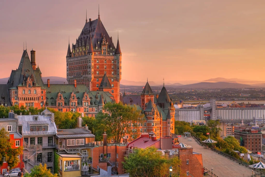 Het imposante hotel Château Frontenac kleurt oranje in de avondzon boven de daken van Québec City