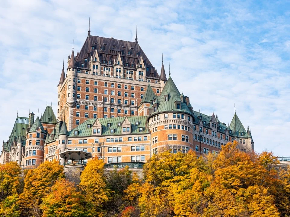 Het kasteelhotel Château Frontenac boven de daken van Québec City omringd door bomen in oranje herfstkleuren