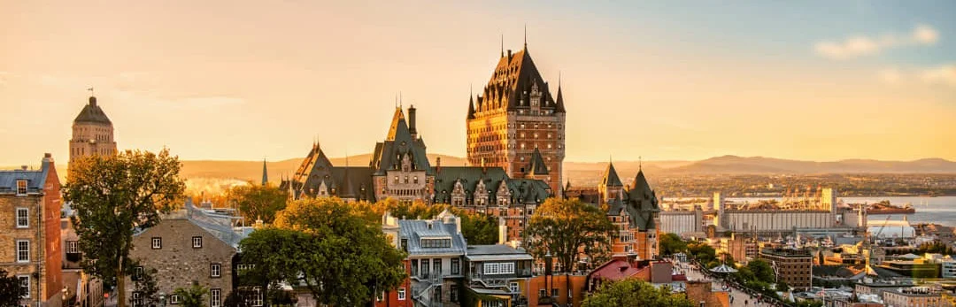 Het kasteelhotel Château Frontenac torent boven de stad Québec City uit in warm oranje avondlicht