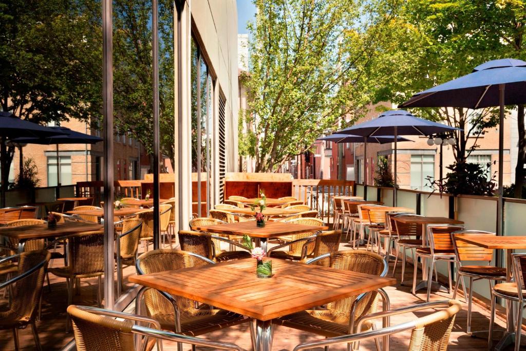 Leeg terras met houten tafels, rieten stoelen en blauwe parasols tussen bomen bij hotel PUR in Quebec City