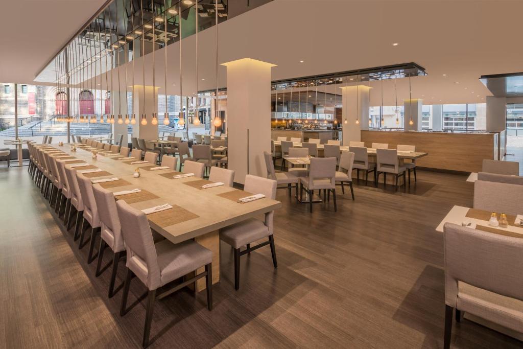 Modern hotelrestaurant met een lange gedekte tafel voor grote groepen en losse tafels op de achtergrond in Quebec City