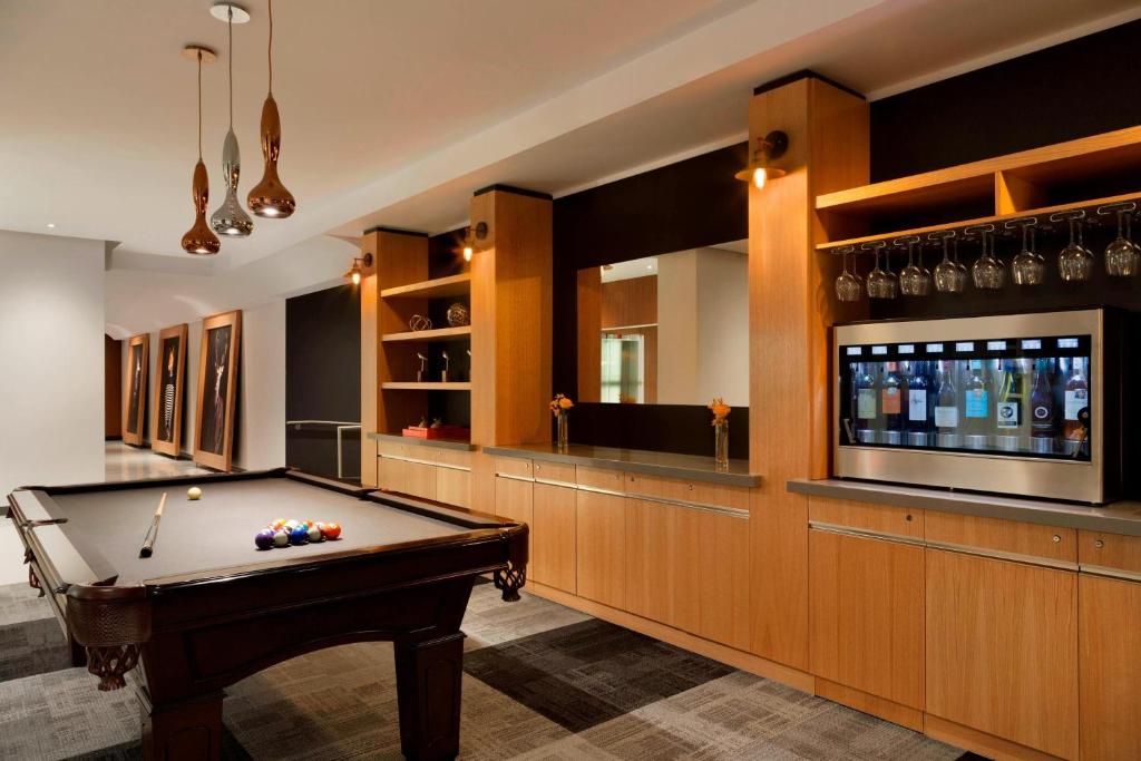 Hotelruimte met een pooltafel op de voorgrond en een bar met wijnkoeling en houten kasten op de achtergrond in Quebec City