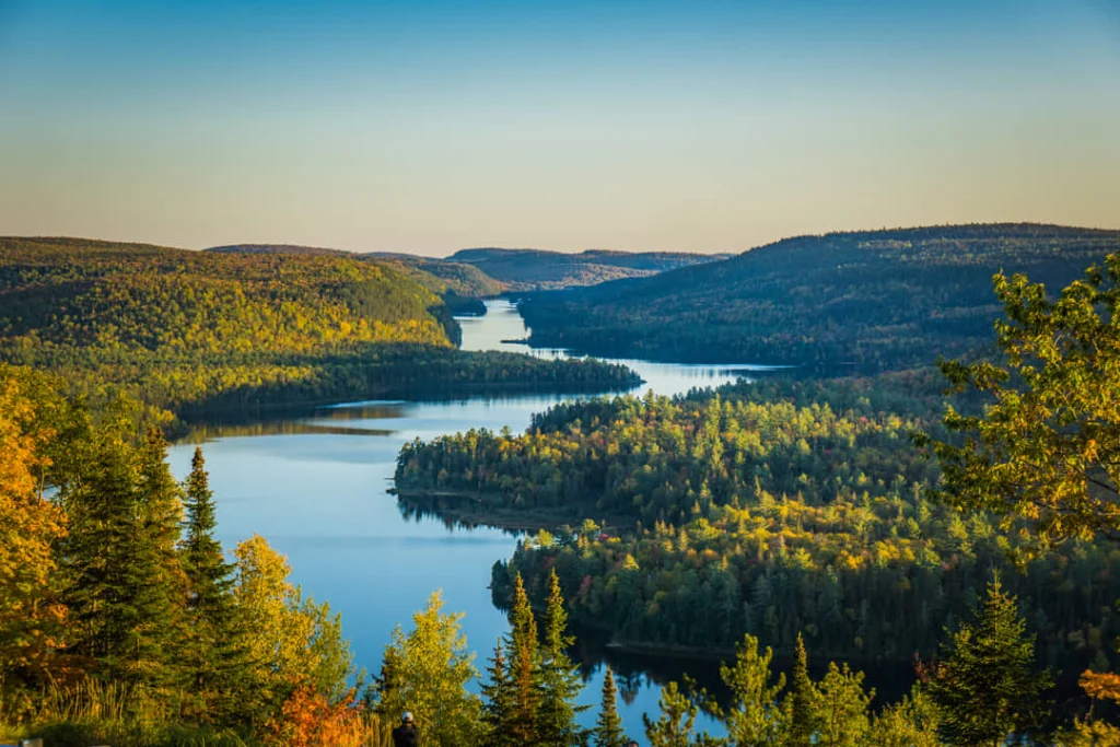 Luchtfoto van een kronkelende rivier tussen glooiende heuvels vol groen en oranje herfstbos in de provincie Quebec