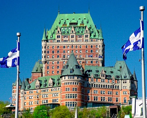 Indrukwekkend kasteelhotel Chateau Frontenac met groene torenspitsen en rode bakstenen gevels tegen een strakblauwe lucht in Quebec Stad