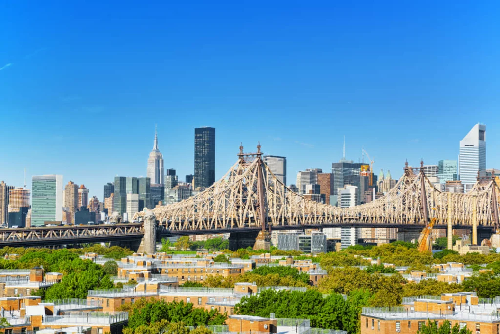 Uitzicht vanaf woonwijken in Queens over de Queensboro Bridge naar de skyline van Manhattan met het Empire State Building