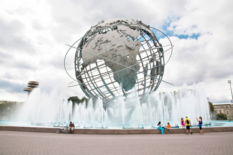 De grote metalen wereldbol Unisphere omringd door spuitende fonteinen in Flushing Meadows Corona Park in Queens, met bezoekers eromheen