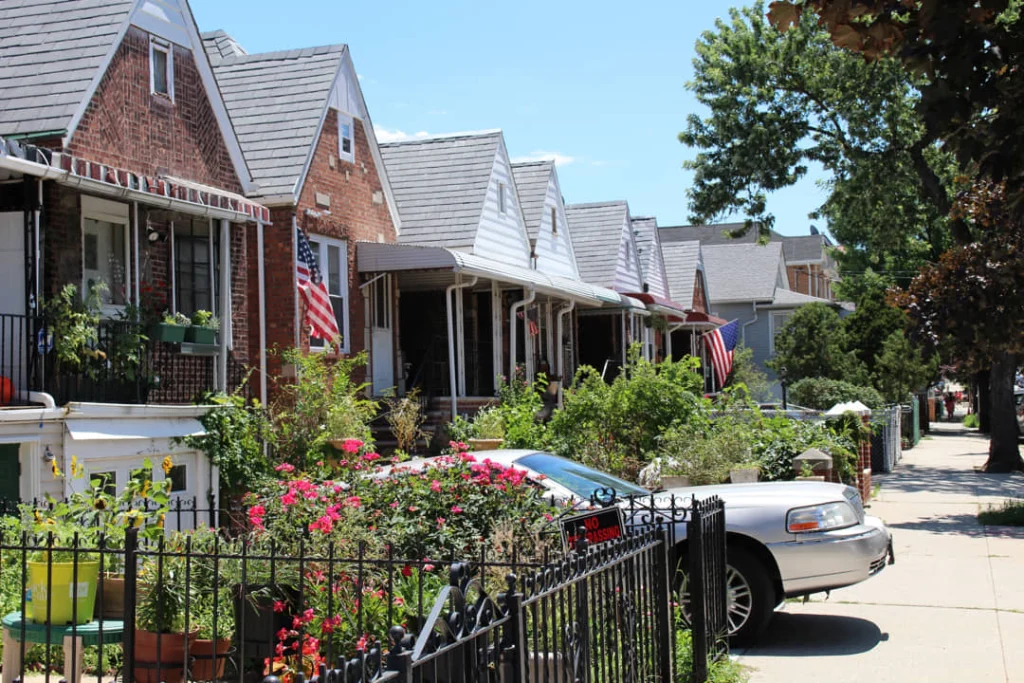 Rustige woonstraat in Queens met bakstenen huizen, veranda's, bloemperken en Amerikaanse vlaggen aan de gevels