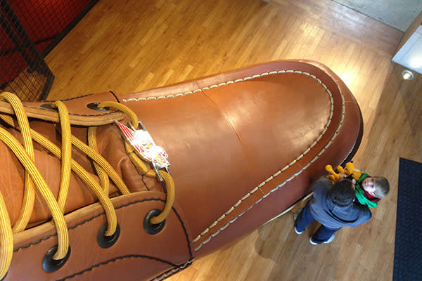 Bovenaanzicht van een enorme bruinleren werklaars in een schoenenwinkel in Red Wing, met bezoekers ernaast voor de schaal