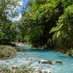 Helderblauwe rivier de Rio Celeste stroomt tussen rotsen door een weelderig groen regenwoud in Tenorio National Park