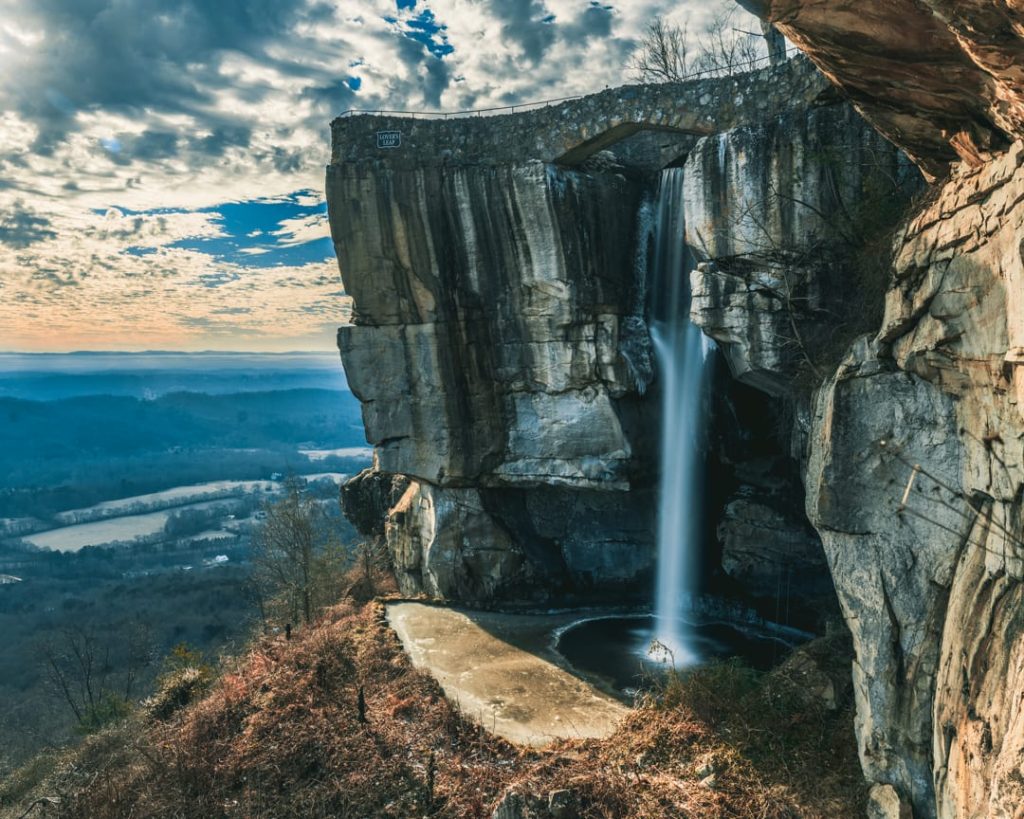 Waterval stort onder een stenen boogbrug in een rotsachtige kloof, met wijds uitzicht over het dal in Rock City
