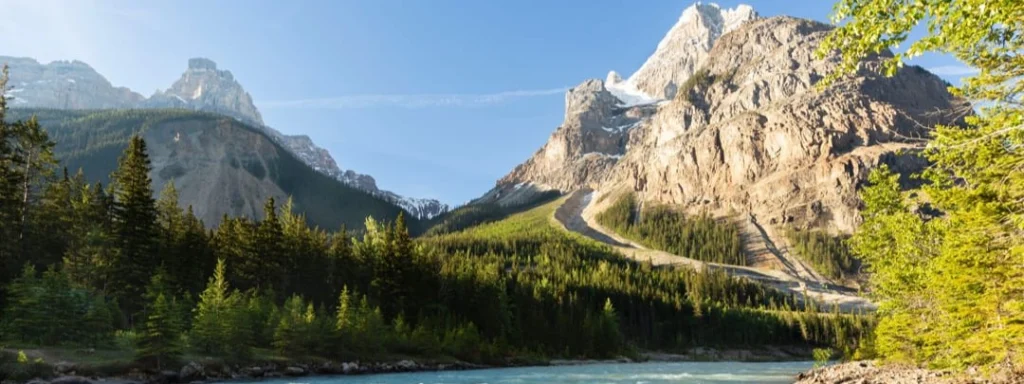 Kronkelende bergweg met haarspeldbochten klimt tegen een steile rotsachtige berghelling boven een turkooizen rivier