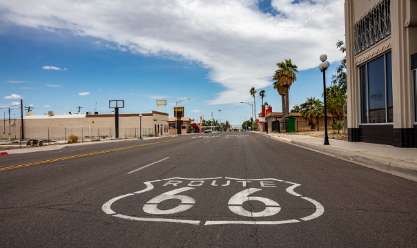 Witte Route 66 wegmarkering geschilderd op het asfalt van een lege straat in een klein woestijnstadje