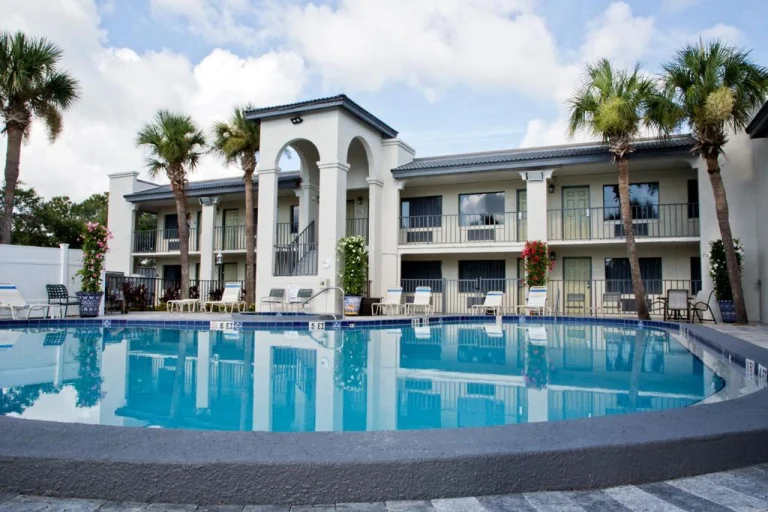 Buitenzwembad met blauw water bij een hotel in Saint Augustine, omringd door palmbomen en ligstoelen op het terras
