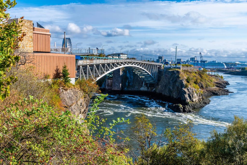 Stalen boogbrug overspant de kolkende stroomversnellingen van de Reversing Falls in Saint John, met de stad op de achtergrond