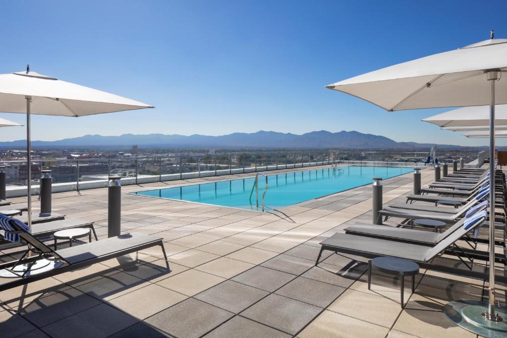 Een zwembad op een dakterras met ligstoelen en parasols kijkt uit over de bergen rond Salt Lake City