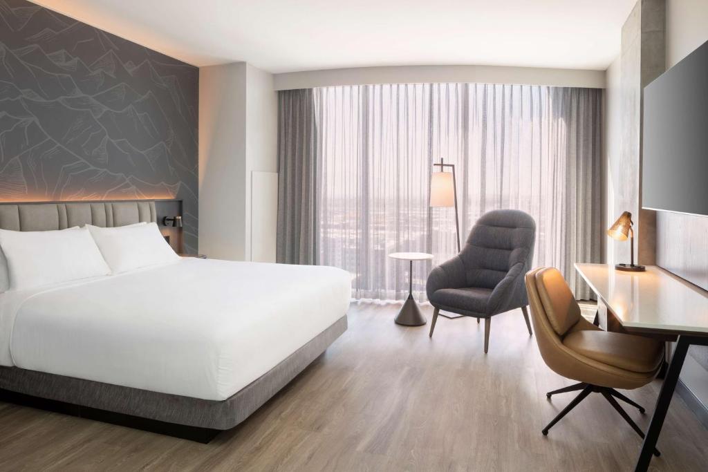 Een hotelkamer met een groot bed voor een hoofdbord met een berg illustratie en een bureau bij het raam
