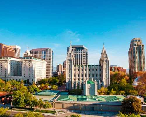 Luchtfoto van de Salt Lake Temple met spitse torens omringd door hoge gebouwen en bomen in het centrum van Salt Lake City