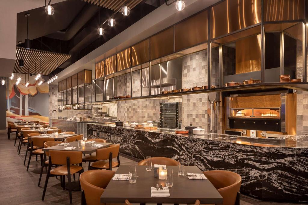 Een modern restaurant met leren stoelen, marmeren bar en een open keuken met houtoven bij een hotel in Salt Lake City