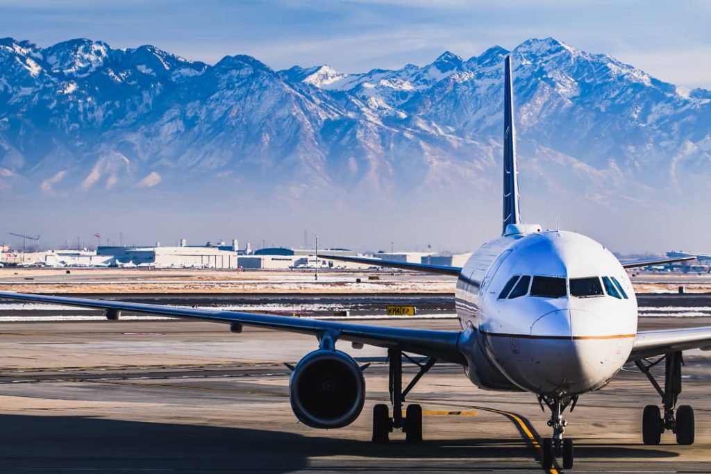 Neus van een passagiersvliegtuig op de startbaan, met de besneeuwde toppen van de Wasatch Mountains bij Salt Lake City