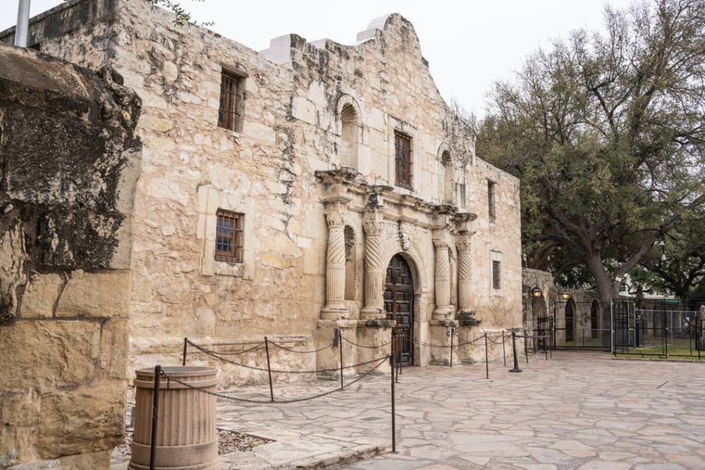Historische stenen gevel van de Alamo missiekerk in San Antonio met een omheind plein ervoor