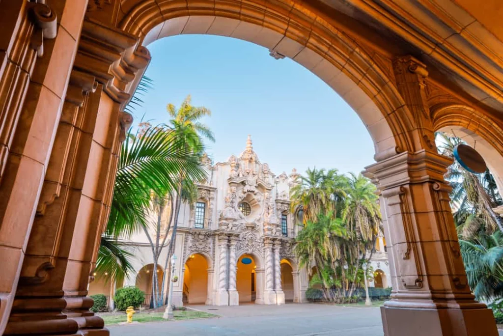 Uitzicht door een gewelfde stenen boog op een rijk versierd gebouw met palmbomen in Balboa Park in San Diego