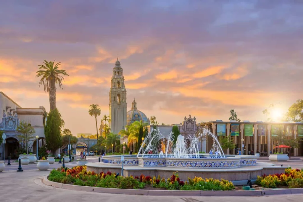 Ronde fontein op een plein in Balboa Park in San Diego met een toren en kleurrijke wolken bij zonsondergang