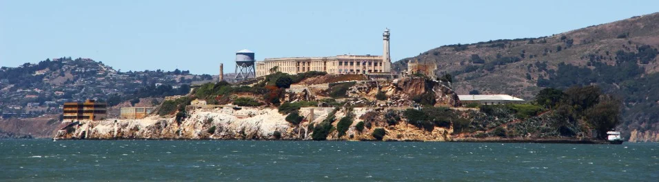 Het voormalige gevangeniseiland Alcatraz met watertoren en gebouwen, gezien vanaf een boot op de baai van San Francisco