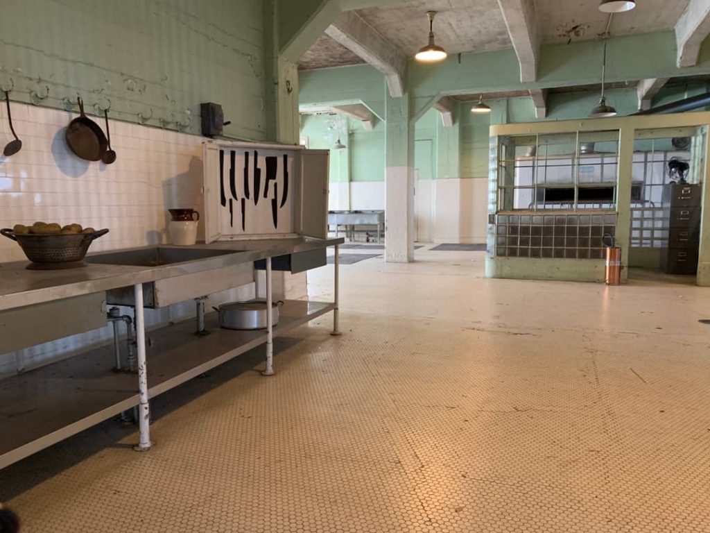 Verlaten keuken van de gevangenis Alcatraz met roestvrijstalen aanrechten, een messenrek en groene betegelde muren
