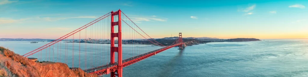 Panoramisch uitzicht op de rode Golden Gate Bridge in San Francisco met de baai en heuvels op de achtergrond bij zonsondergang
