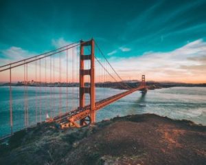 De oranjerode Golden Gate Bridge over de baai met de skyline van San Francisco op de achtergrond onder een kleurrijke avondlucht