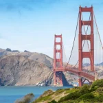 De rode Golden Gate Bridge over de baai, met groene heuvels en bomen op de voorgrond in San Francisco