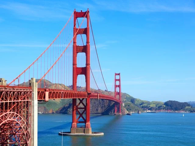 Close-up van de rode toren en kabels van de Golden Gate Bridge, gezien vanaf het voetpad met verkeer op de brug