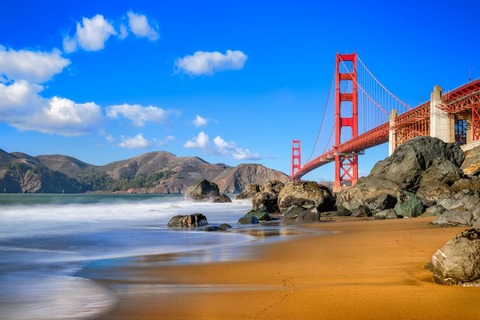 De rode Golden Gate Bridge in San Francisco gezien vanaf een zandstrand met rotsen en heuvels op de achtergrond
