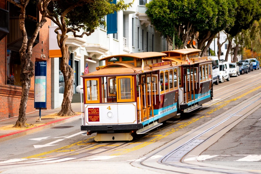 Kleurrijke kabeltram rijdt door een straat met karakteristieke huizen in San Francisco op een zonnige dag