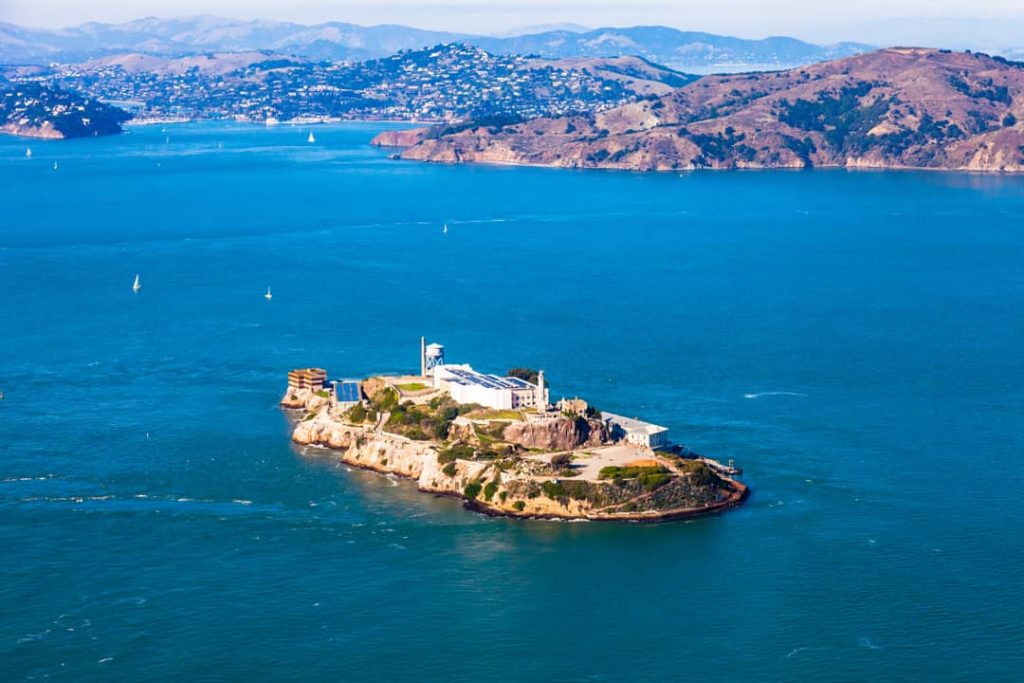 Luchtfoto van het rotsachtige gevangeniseiland Alcatraz omringd door blauw water met de heuvels van Sausalito op de achtergrond
